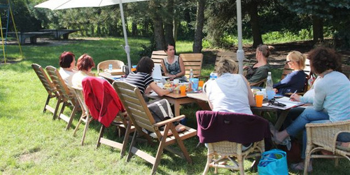 Menschen sitzen an einem Tisch unter Sonnenschirmen